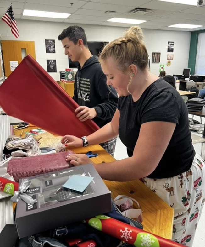 Pictured are two Bible club students at MuHS as they wrap gifts for a family within the Applemen community.